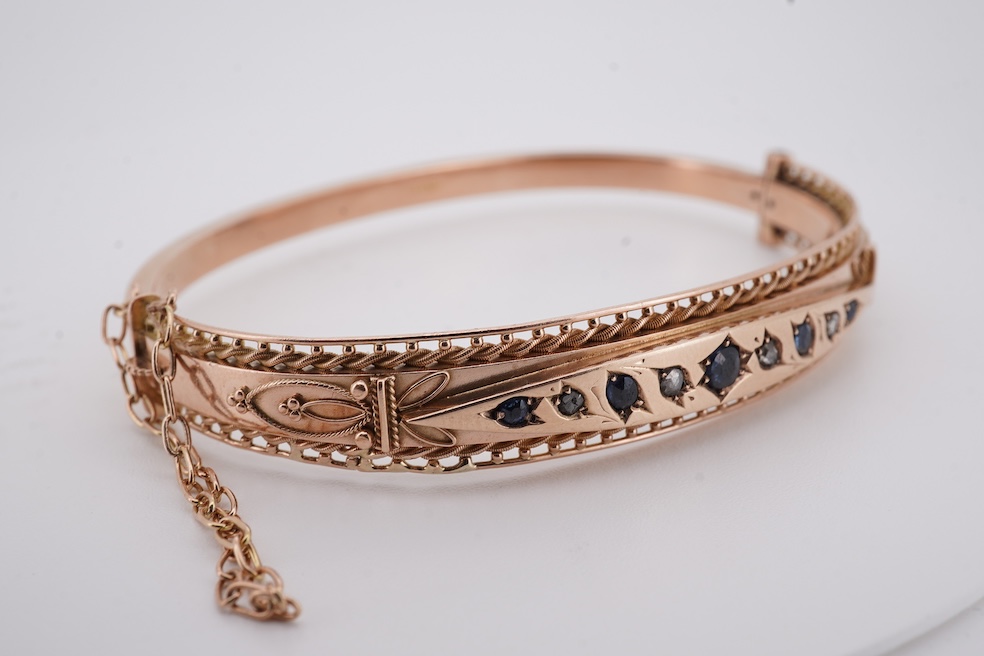 An Edwardian 9ct gold, sapphire and diamond set hinged bangle, Chester, 1909, interior diameter 57mm, gross weight 10 grams. Condition - poor